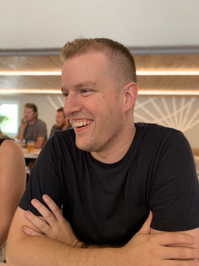 A three quarter view of Matt smiling at an indoor social event